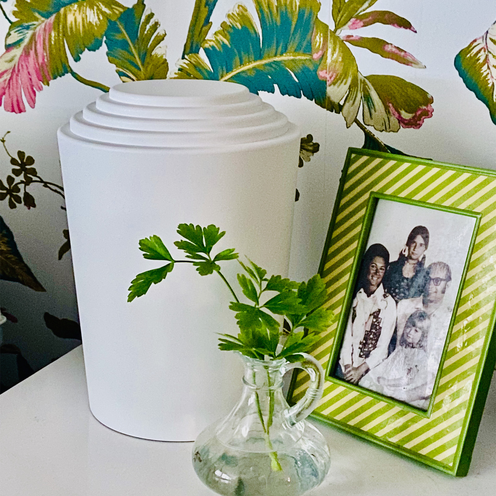 a white custom urn on a side table next to a family photo