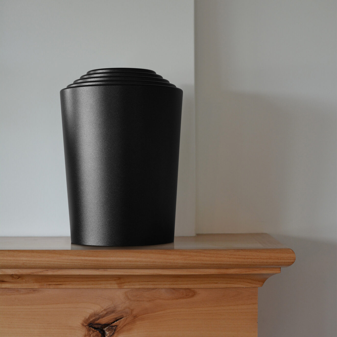 a charcoal timeless series modern cremation urn by Everkeep Memorials sitting on a mantel