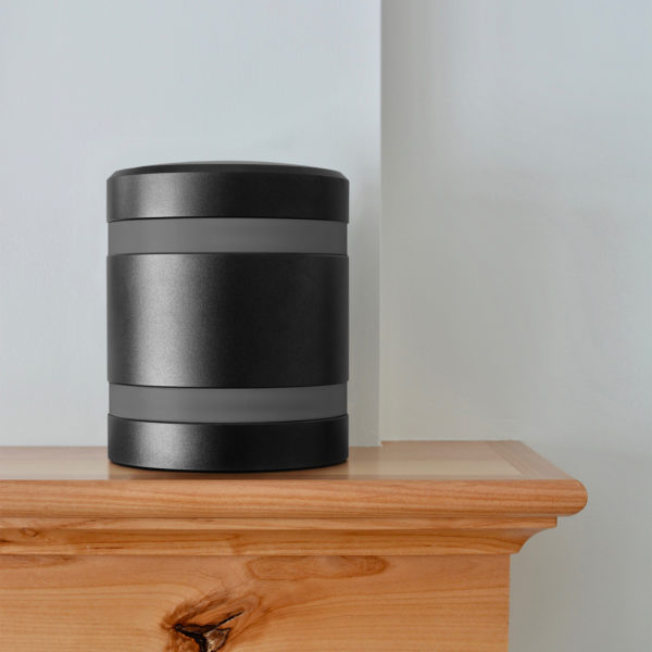 a black metal infinite series modern cremation urn with dark gray bands sitting on a mantel.