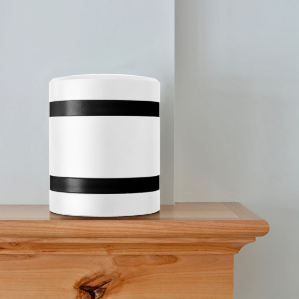 a white metal infinite series modern cremation urn with black bands sitting on a mantel.