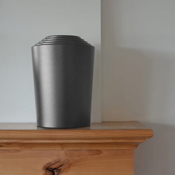 a grey timeless series modern cremation urn sitting on a mantel on full display