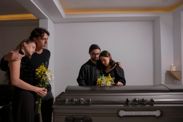 a couple embracing each other while standing over a casket